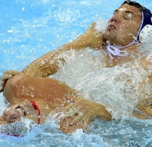 Team USA defender Jesse Smith (11) battles with Romainia's center forward Mihnea Chioveanu (8) in front of the goal during the London 2012 Olympic Games at Water Polo Arena.